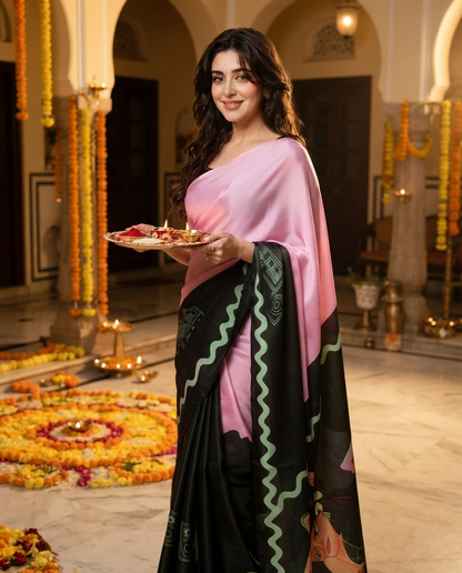A woman wearing a pink and black sari with green zigzag patterns stands in a decorated indoor hall, holding a tray with lit candles.festival, rakshabandhan