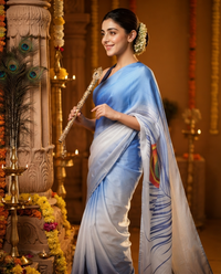 A woman wearing a light blue and white sari with a peacock feather print, holding a decorative gold flute in a beautifully decorated temple setting.janmashtami, festival,